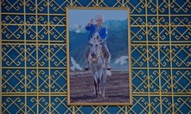 A portrait of president Gurbanguly Berdymukhamedov astride an Akhal-Teke horse welcomes spectators within primary hippodrome entry.